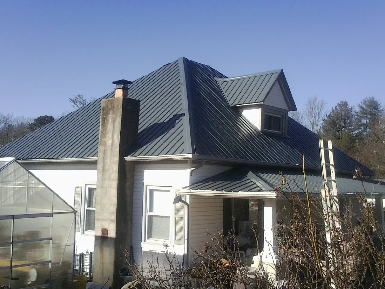 Dark blue standing seam metal roof on a white farmhouse with dormer — Slate & Tile Roof Repair by Roofing Brothers in Gervais