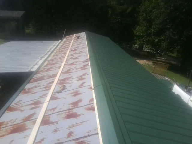 Old rusted panels beside newly installed green metal roofing — Wind Damage Roof Repair by Roofing Brothers in Gervais