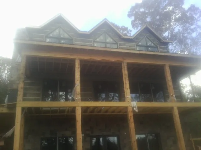 Dormers and porch framing on a large log home under construction — Roof Coating work by our crew in Gervais