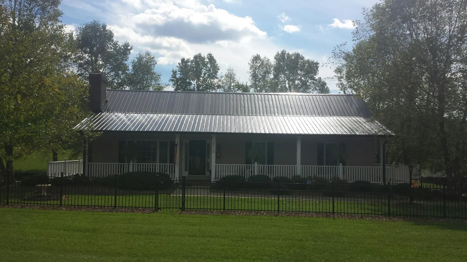 Gray metal roof on a brick ranch with a full width front porch — Gutter Guard Installation work by our crew in Gervais