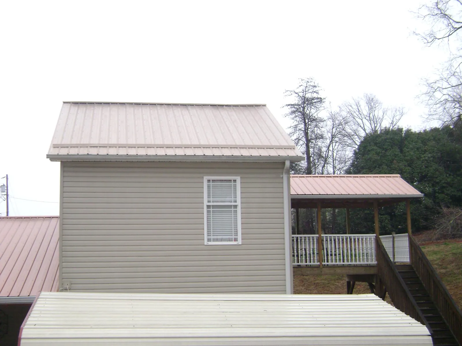 Tan metal roofs on a two story addition and attached porch, from a Roof Replacement job in Gervais