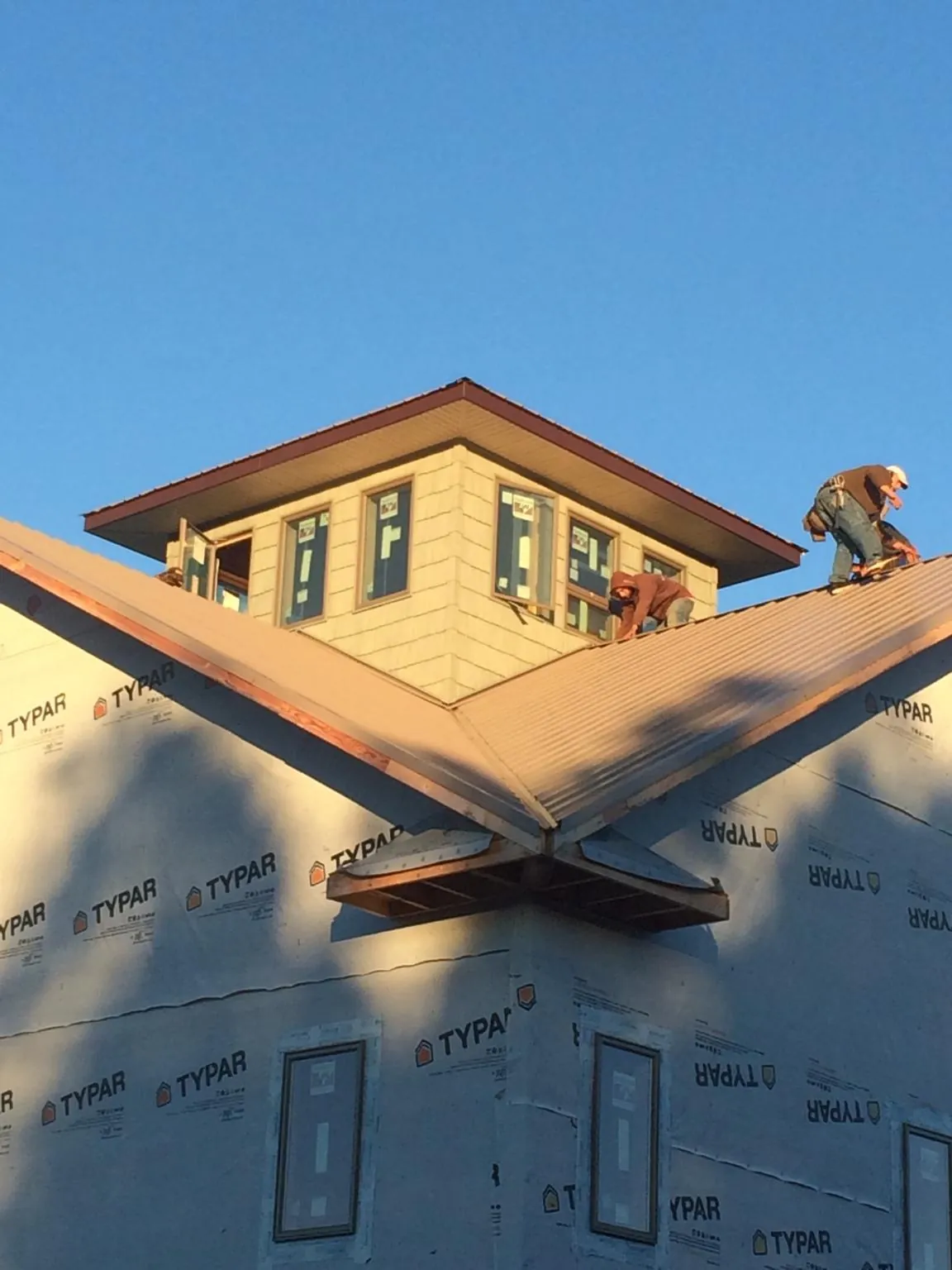 Roofers working around a rooftop cupola on a new metal roof at sunset — Roof Waterproofing in Gervais by Roofing Brothers